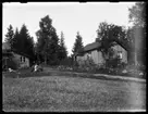 Ladugården med tillbyggnad och bostadshuset på Torpängen. Nils, Hjärtum 1918-01-09, Olga, född Olsson, Forshälla 1891-05-12, Erik, Hjärtum 1919-07-26 med katten i knät, Sven, Hjärtum 1915-05-14.