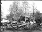 Familjen Jonssons rödmålade bostadshus med vita knutar och tvåkupiga tegelpannor på taket. Sven, Hjärtum 1915-05-14, Nils, Hjärtum 1918-01-09,  Erik, Hjärtum 1919-07-26, Olga, född Olsson, Forshälla 1891-05-12 och Olofs syster Jeanna Jonsson, Hjärtum 1874-04-03. I bakgrunden syns Öresjö och vägen mellan Sågbron och Nötbron, Fjällvägen med sina stengardister. Vid sidan av huset ligger tegelrör till dränering.