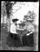 Signe Högberg, Väne-Ryr och Alma Johansson, Hjärtum 1888-03-31, vid ett litet bord i trädgården på Torpet (Arnstorp). Öresjö skymtar i bakgrunden.