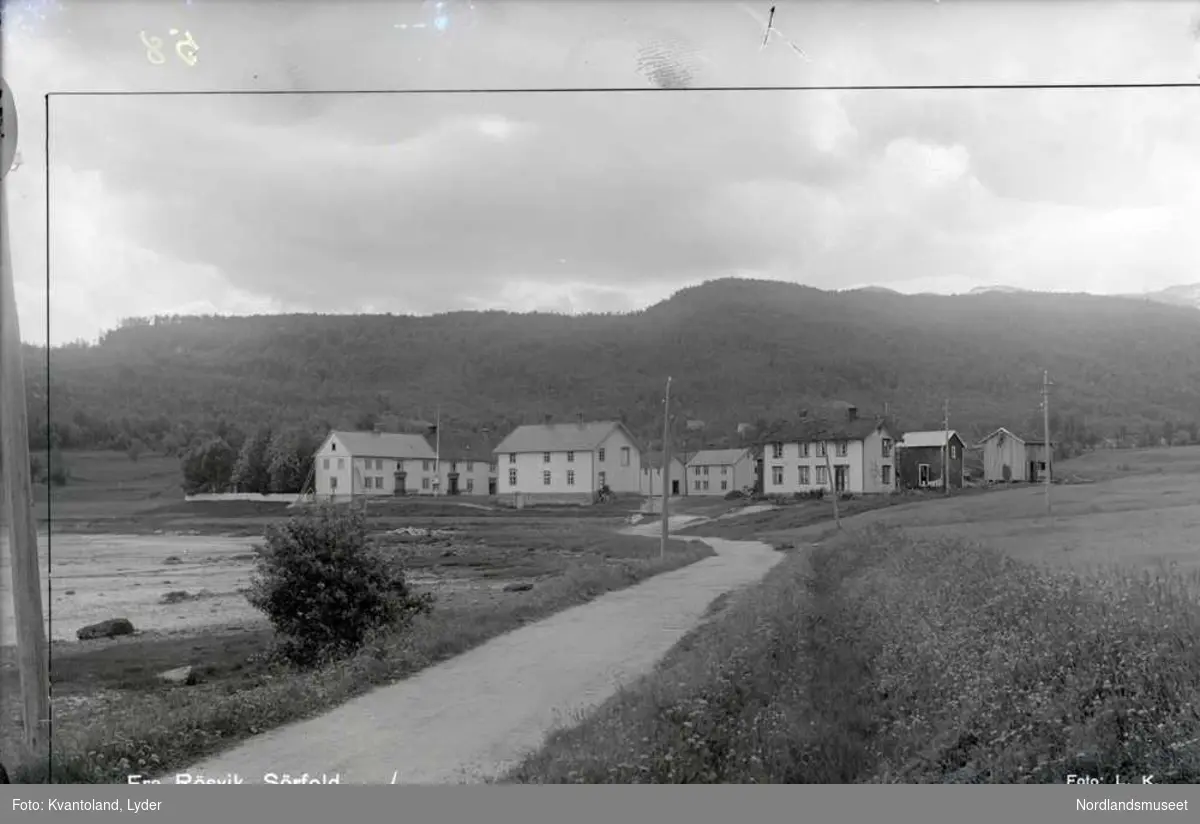 Fra Røsvik, Sørfold
Kvantolands protokoll: Røsvik hovedgård, prosp.
Ekstern kommentar: Huset fremst til høyre tilhørte Henrik Mikal Strøksnes (1879-1941).
Ekstern kommentar(2): "Dette bildet er ikke fra 1930. I 1928 sto det nye bankbygget ferdig, og det ville ha vært med på bildet til venstre hvis bildet var fra 1930. "