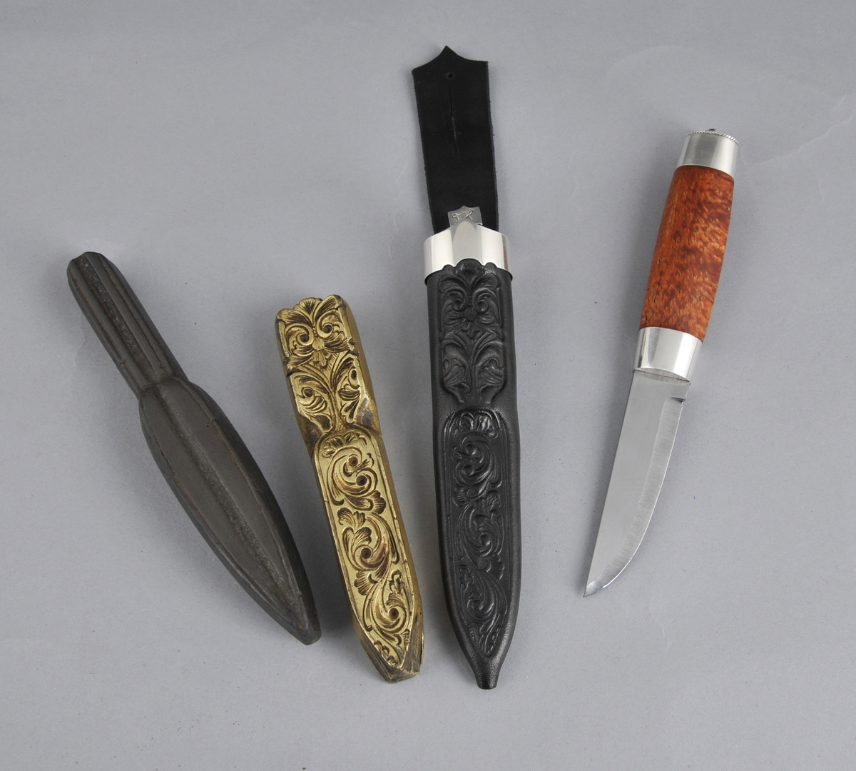 Kniv med slire. Slira er trykt og læret er tysk rårand. Øverst er det ein sylvholk med ein spiss oppover i front og ein svak profilering i underkant  Knivskaftet er laga av valbjørk med sylvholkar oppe og nede. På toppen av holken er det ei svakt boga, oval sylvplate med ein sylvkule på toppen og åtte gravera strekar ut mot kanten som har ein tvinna slyvtråd (filigran) som avslutning. Knivbladet er laminert jarn og stål.