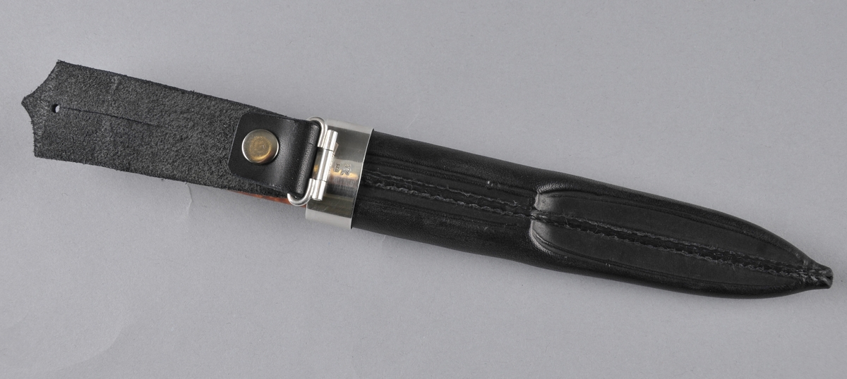 Kniv med slire. Slira er trykt og læret er tysk rårand. Øverst er det ein sylvholk med ein spiss oppover i front og ein svak profilering i underkant  Knivskaftet er laga av valbjørk med sylvholkar oppe og nede. På toppen av holken er det ei svakt boga, oval sylvplate med ein sylvkule på toppen og åtte gravera strekar ut mot kanten som har ein tvinna slyvtråd (filigran) som avslutning. Knivbladet er laminert jarn og stål.