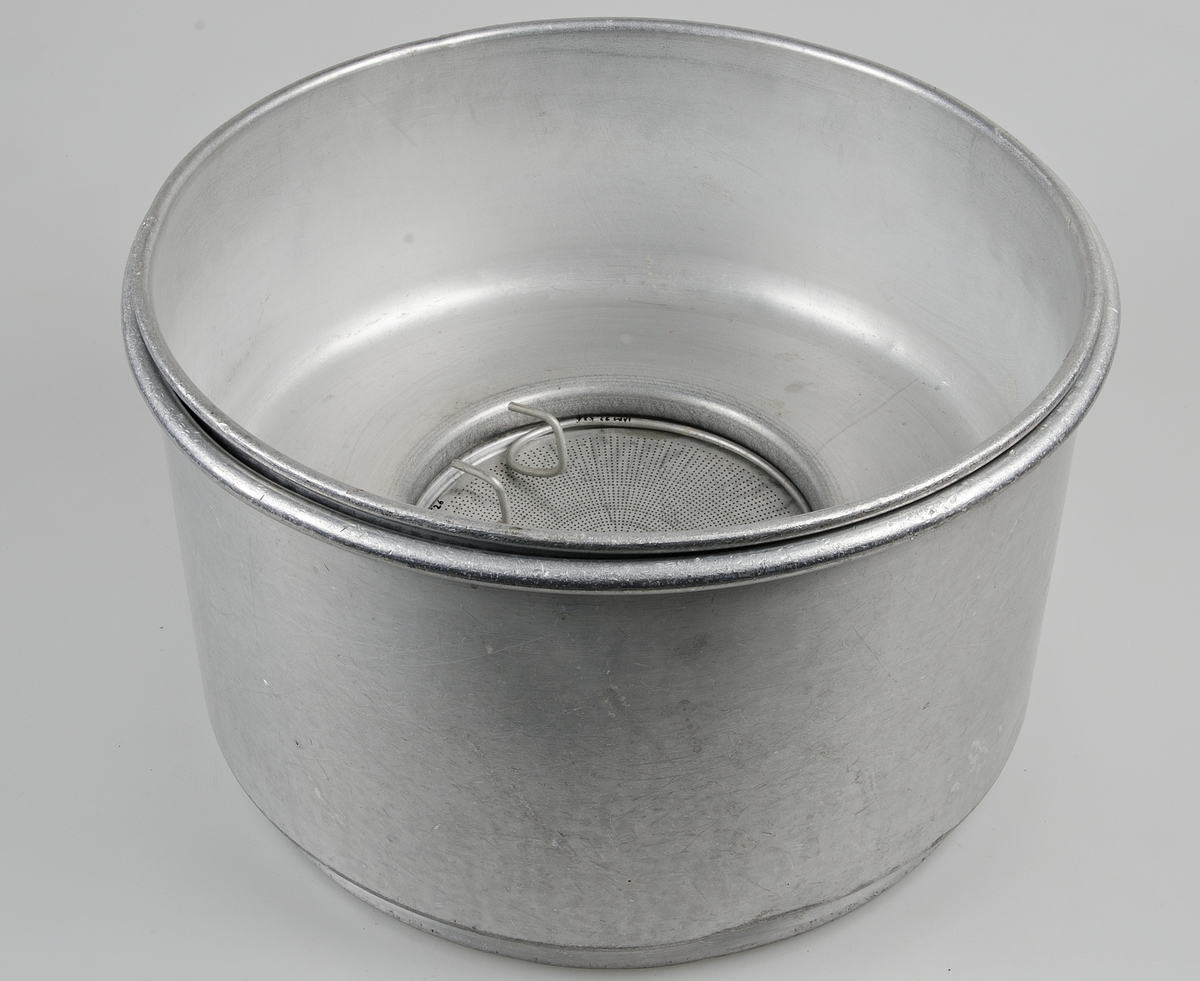 Apparat av aluminium för silning och kylning av mjölk. Hela apparaten består av sju delar:
1) ring för applicering på mjölkflaska.
2) kyldel, konisk, med dubbla väggar, avtappningskran av mässing, tillflödesskiva, gummislang.
3) mellankärl med små hål för att få mjölken att rinna längs väggarna i del 2
4) mjölksil med stort hål för att få mjölken att rinna längs väggarna i del 2
5) silplatta med många fina hål
6) silplatta med grövre och färre hål
7) ring för fasthållande av filter och sil, ett antal pappersfilter medföljer.