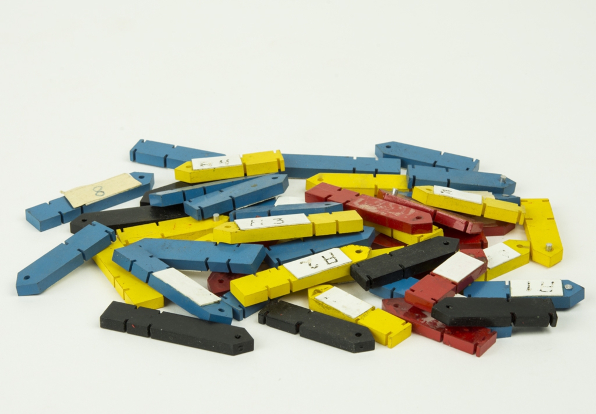 Markerbricka bestående av 16 st röda, gula, blå och vita urtavleliknande cirklar, samt 44 st röda, blå, gula och svarta plastpilar. Sammanhör med ett större parti brickor, pilar och tecken.
