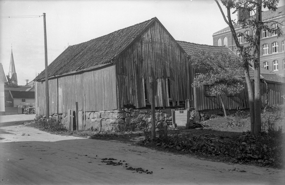 Løe bak Breidablikk skole. I bakgrunnen tårnet fra Vår frelsers kirke. Noen få trær til høyre.