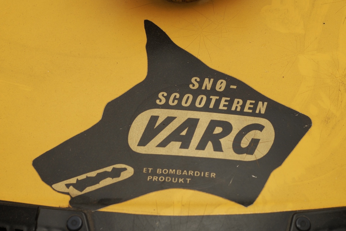 Motorisert gjenstand med drivbelte, 2 styreski, totaktsmotor og gult karosseri. Det er en avlang salpute med ryggstøtte. Sprekk i salen.