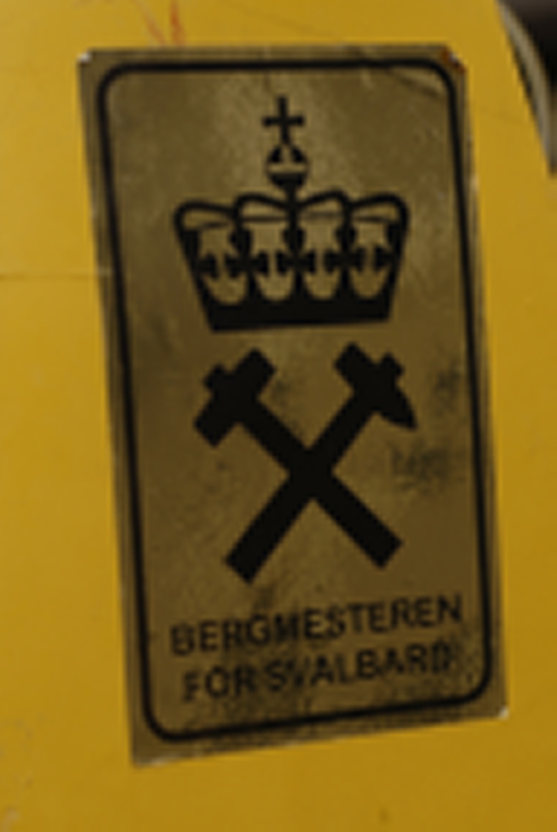 Motorisert gjenstand med drivbelte, 2 styreski, totaktsmotor og gult karosseri. Det er en avlang salpute med ryggstøtte. Sprekk i salen.