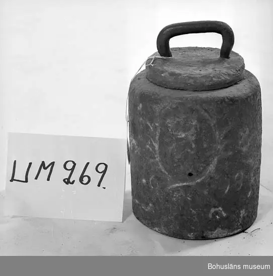 Järnlod med platta av justeringsbly ovanpå lodet. 
Lodet väger 160 pund (10 lispund) vilket motsvarar omkring 80 kilo.  
På cylinderns sida avtecknar sig i relief kung Christian V:s krönta  monogram. 

Ur handskrivna katalogen 1957-1958:
Järnvikt 1698, dansk.
H. 34, D. 23 cm; till största delen bly; järnhandtag. 1698 med lagerkrans omramande en krönt krona med kungligt namnschiffer; vikt 85 kg. Hel.

Ur handskriven katalog över Uddevalla Musei Historiska Samlingar, svenska avdelningen, yngre föremål upprättad  år 1916 av intendent Knut Adrian Andersson:
No 21 Svensk järnvikt à 85 kilo, använd
i Uddevalla. Krönt 1698. Skänkt av
disponenten Robert Bley vid Kampenhofs fabrik
9 April 1919.