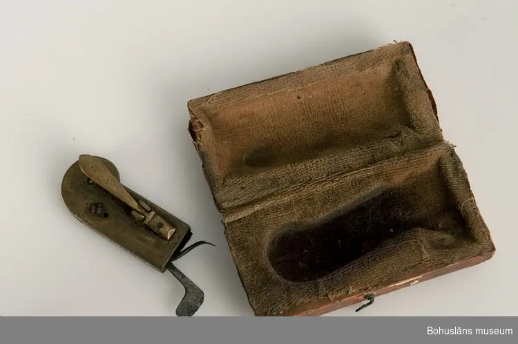 Ur handskrivna katalogen 1957-1958:
Snäppa
Snäppan a) L. 5,8 cm; mässing m. mekanismer av järn. Fodralet b) 7,2 x 3,7 x ,1 cm; trä, papper på utsid., tyg på insid. Trasigt.

Lappkatalog: 94