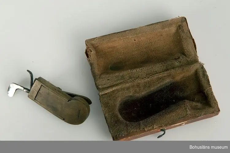 Ur handskrivna katalogen 1957-1958:
Snäppa
Snäppan a) L. 5,8 cm; mässing m. mekanismer av järn. Fodralet b) 7,2 x 3,7 x ,1 cm; trä, papper på utsid., tyg på insid. Trasigt.

Lappkatalog: 94