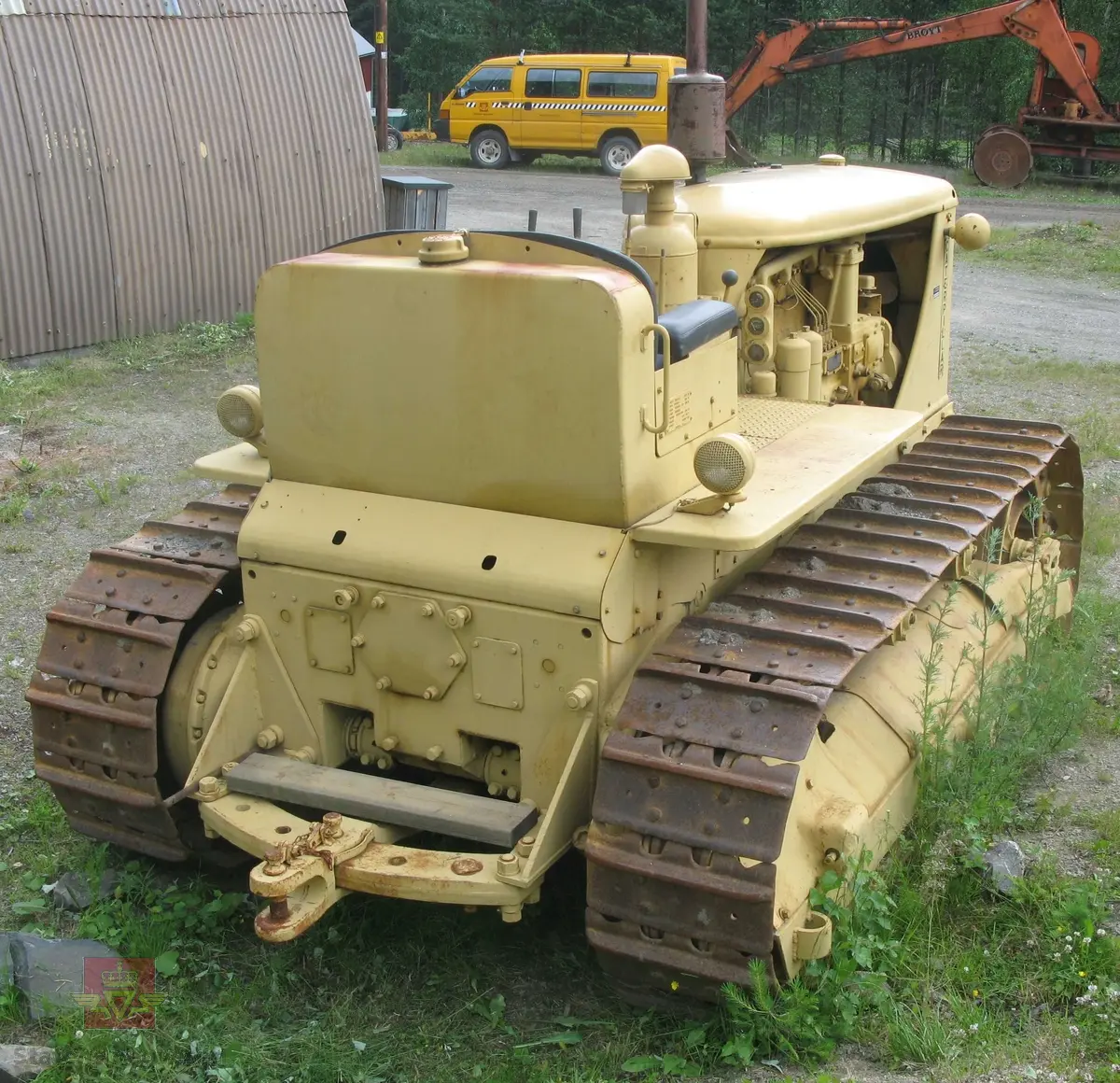 Caterpillar D 7. Gul, (opprinnelig grønn), med svart sete. Maskina er egentlig en bulldozer, men denne er bygget som beltetraktor. Forskjellen ser man best på den bredere fronten hvor det ikke er plasss til hydrauliksylindre for løft av bulldozerskjær. Denne har likevel hatt et skjær, men løfteanordningen som ble benyttet var vinsjen som satt bak på maskina. Wirene gikk fra vinsjen og over to tårn og videre ned på skjæret. Maskina har en 4-sylindret dieseldrevet motor som yter ca 128 Hk. Startmotoren er bensindrevet.
Oppstarting av dieselmotorene er såpass spesiell at den beskrives her:
Starteren er en 2-sylindret bensinmotor. Etter å ha skrudd opp bensinkrana og slått på tenningsbryteren på ON, settes sveiva ned gjennom panseret. Choken må setes på etter behov og gasspjeldet må settes på litt over tomgang. Startmotoren dras over komp. til den starter. Startmotoren bør gå noen minutter fordi avgassene varmer opp dieselmotorens innsugningsrør. Dieselmotorens gasshåndtak settes på halv gass, og dekompresjonshåndtaket på siden av motoren settes til, (slik at motoren går lett rundt).
Det finnes to håndtak for å koble til driften mellom starter og hovedmotor, det ene for å flytte "bendixdrevet" i inngrep med svinghjulet og det andre håndtaket er en clutch som setter i gang bevegelsen av dieselmotoren. Man kjører da noen omdreininger får så å sette dekompresjonshåndtaket i halvstilling. Når man ser på eksosen at dieselen begynner å forbrenne slår man håndtaket over på full kompresjon. Etter noen omdreininger går hovedmotoren av seg selv, slik at starteren kan kobles fri og bensinkrana stenges og tenning slåes av.