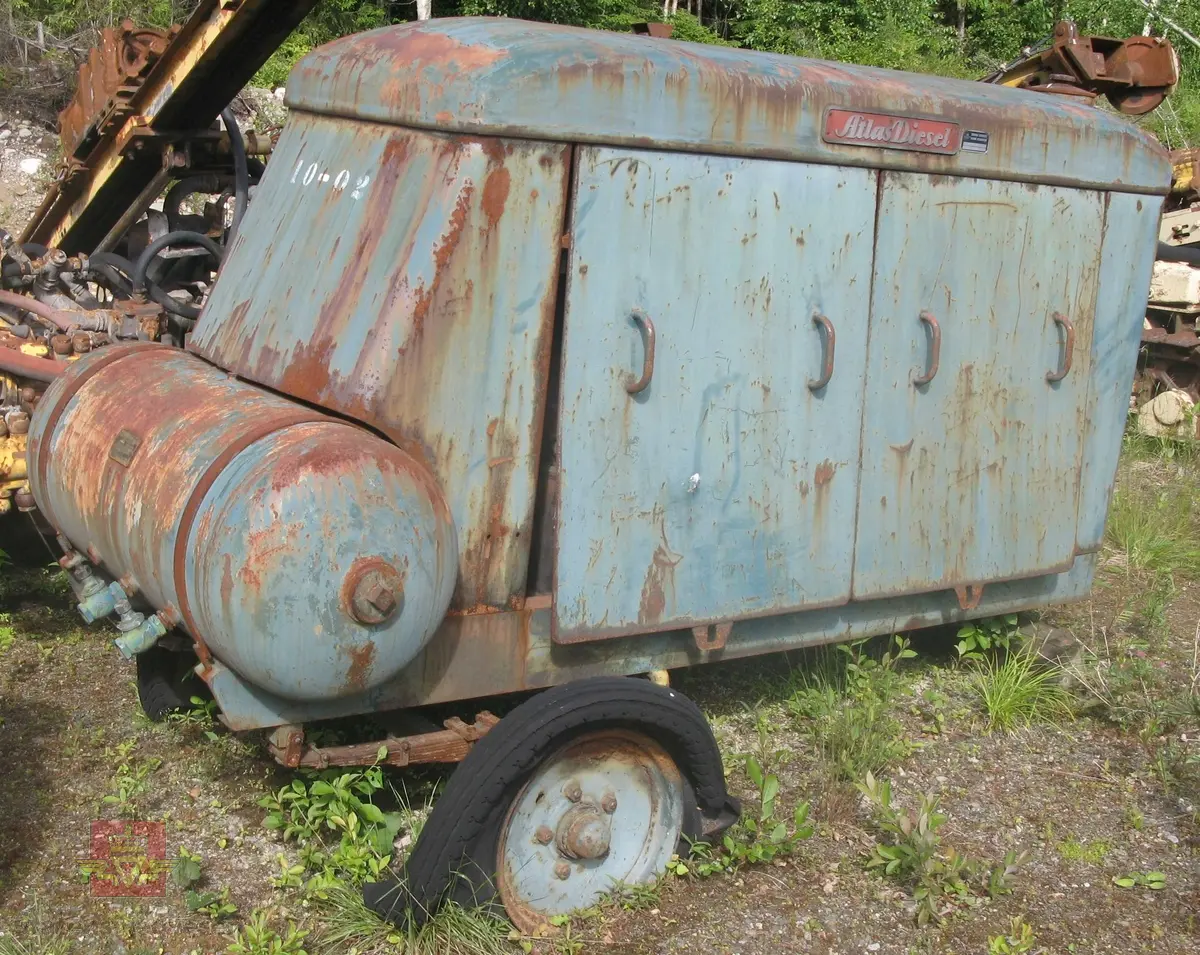 Transportabel kompressor, skal være 2-akslet med 4 luftfyllte gummihjul, (her mangler en aksling). Grønn med rød drivmotor og kompressor. Motoren er en dieseldrevet 4-sylindret type fra Atlas Diesel. Kompressorenheten er 3-sylindret, av typen FR4V, med trykktank. Kompressoren og tanken er også  Atlas Diesel produkter. Maskina har merking fra produsenter. Vi antar at kompressorens kapasitet er 7,2 kubikkmeter luft i minuttet og at motoren yter ca. 70 hk.
Mangler deler.
