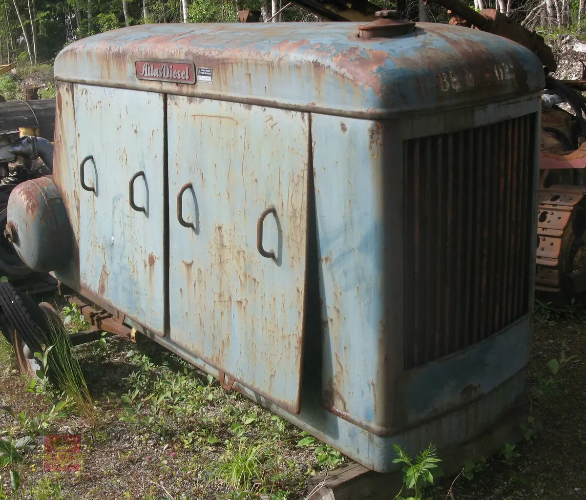 Transportabel kompressor, skal være 2-akslet med 4 luftfyllte gummihjul, (her mangler en aksling). Grønn med rød drivmotor og kompressor. Motoren er en dieseldrevet 4-sylindret type fra Atlas Diesel. Kompressorenheten er 3-sylindret, av typen FR4V, med trykktank. Kompressoren og tanken er også  Atlas Diesel produkter. Maskina har merking fra produsenter. Vi antar at kompressorens kapasitet er 7,2 kubikkmeter luft i minuttet og at motoren yter ca. 70 hk.
Mangler deler.
