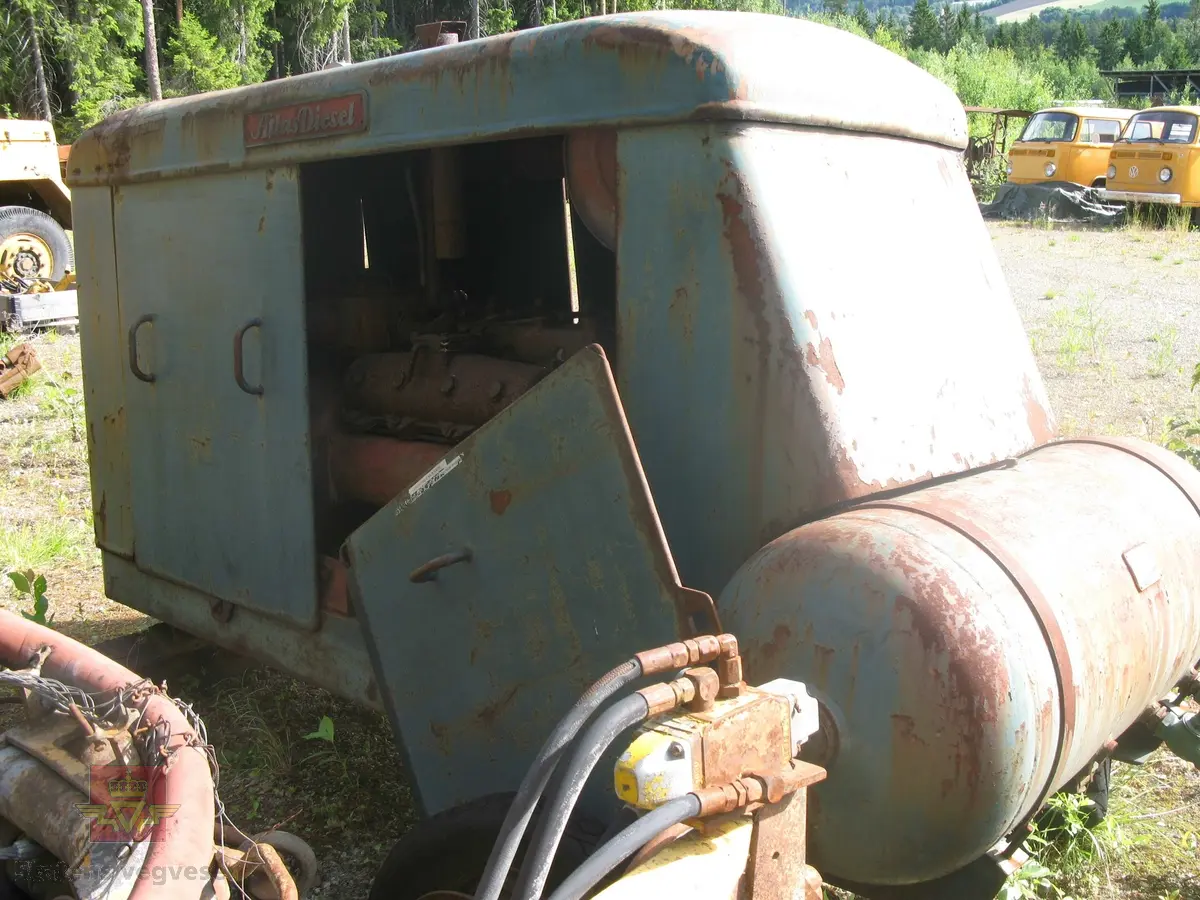 Transportabel kompressor, skal være 2-akslet med 4 luftfyllte gummihjul, (her mangler en aksling). Grønn med rød drivmotor og kompressor. Motoren er en dieseldrevet 4-sylindret type fra Atlas Diesel. Kompressorenheten er 3-sylindret, av typen FR4V, med trykktank. Kompressoren og tanken er også  Atlas Diesel produkter. Maskina har merking fra produsenter. Vi antar at kompressorens kapasitet er 7,2 kubikkmeter luft i minuttet og at motoren yter ca. 70 hk.
Mangler deler.
