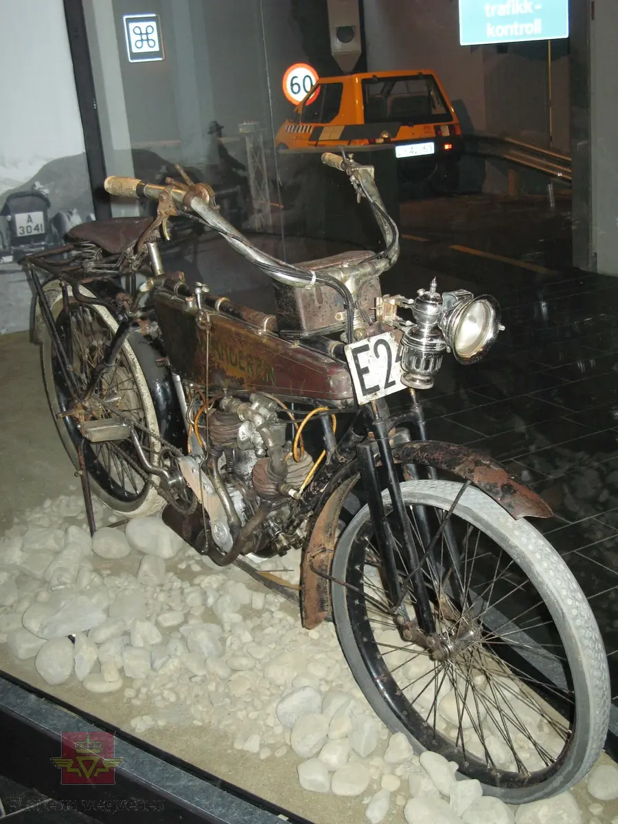 Wanderer 3 PS. Tohjuls motorsykkel, svart, brun og grønn med staffering og merking i rødt. Motorsykkelen har en 2-sylindret bensindrevet V-twin motor med sylindervolum 404 cm3 og en ytelse på 3,5 hk. Sykkelen har merking fra produsenten. Det er også et utdatert kjennemerke festet til sykkelen. Dekkdimensjon er 650-55.