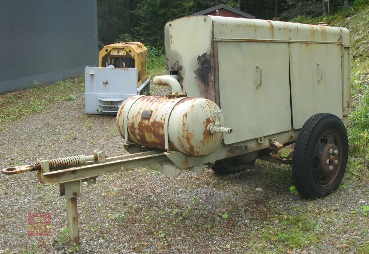 Transportabel kompressor, 1-akslet med 2 luftfyllte gummihjul, (trolig kompaktgummi opprinnelig). Grønn med grønn drivmotor og kompressor. Motoren er en dieseldrevet 4-sylindret to-takts type med kruttstart. Selve kompressordelen er 2-sylindret. Både dieselmotoren og kompressoren er produkter fra Atlas Diesel. Enheten kalles Mono-block, (har felles veivhus og bunnpanne). Vannavkjølt. Kompressoren har drag med støttebein. Merking fra produsent. Antatt kapasitet er 3 kubikkmeter luft i minuttet.