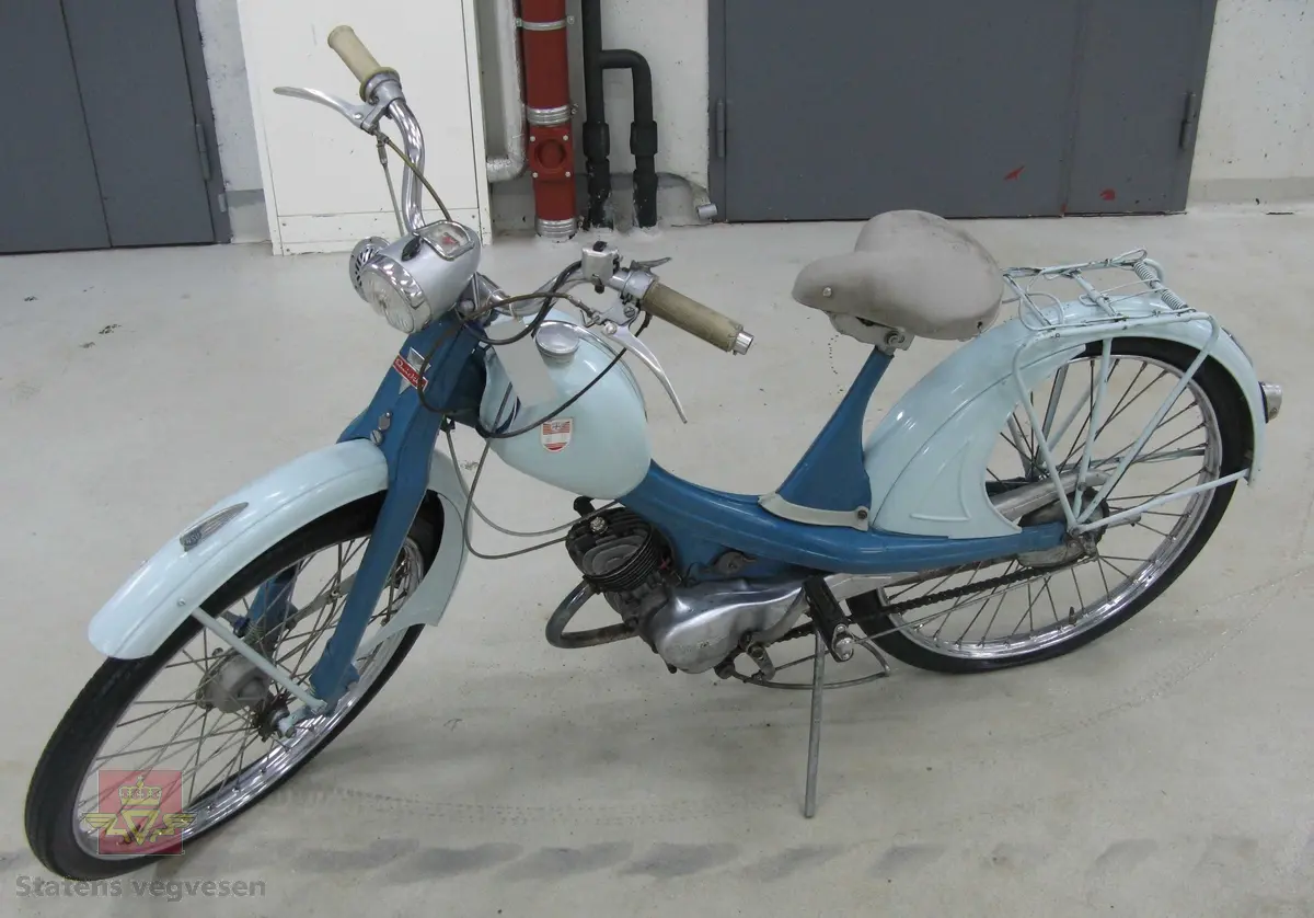 NSU Quickly. 2-hjuls moped med pedaler, (for å bidra til fremdrift). To farget blå med grått sete og styreholker. Merking i rødt og blått. Lykt foran og refleks bak. Merking på motoren viser at motortypen heter 51 ZT, med størrelse 49 ccm. Motornummer er 459127. Sylinderen i motoren er trolig mindre enn det merkeplata tilsier, (se historikk). 
Tidsriktig kåpe og sylinder med størrelse 49 ccm følger med mopeden. (disse gjenstandene har aldri vært brukt på akkurat denne mopeden, men på tilsvarende mopeder).