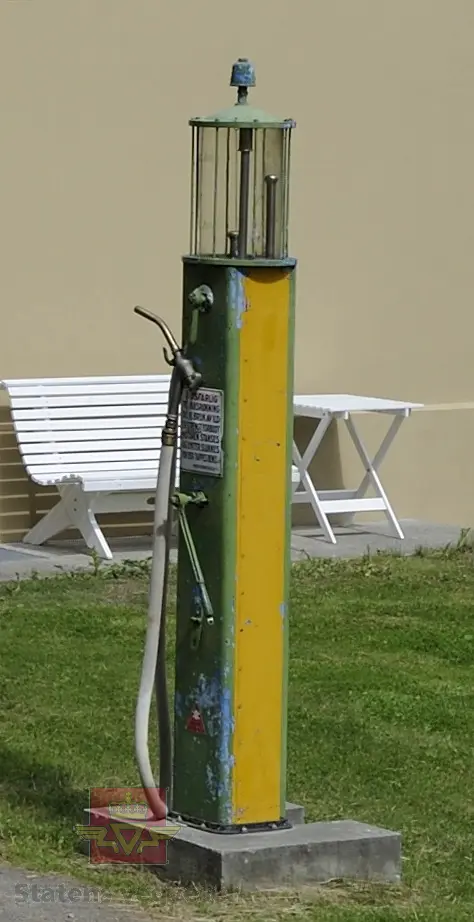 Flerfarget, hovedfarger er grønn og gul, (opprinnelig blå). Håndpumpe og porsjoneringsglass. Står på sokkel. Merking.
Trekasse med lokk høre til pumpa.