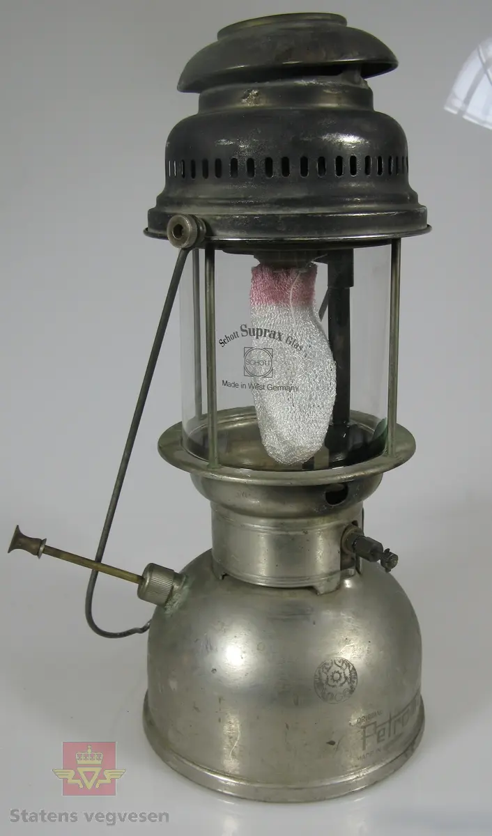 Bærbar parafinlykt av metall og glass. Har ikke veike, men nett.  Lampa fungerer slik at en pumper på trykk, som på en primus.
Merking på glass: Schott Suprax Glas Made in West Germany
Merking på lykt: ORIGINAL Petromax MADE IN GERMANY  REG. 826/350 CP SUPER ORIGINAL Petromax

En eske med ekstra nett følger med, registrert som NVM 00-G-03054-1.