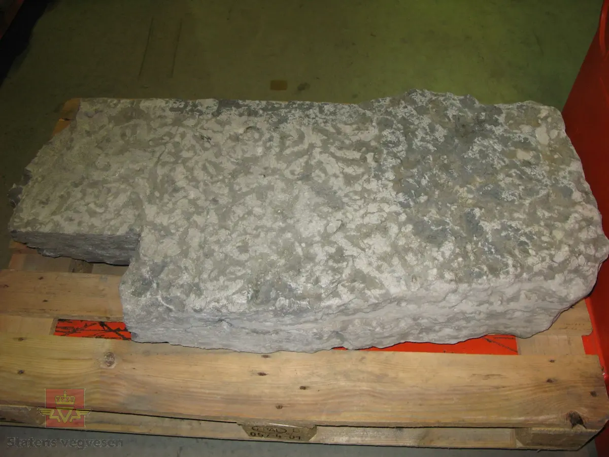 Grå kalkstein i 5 deler. Noe av monogrammet er borte, men 1687 er godt synelig. Kun den største delen er merket. Steinen er lagret på to paller.