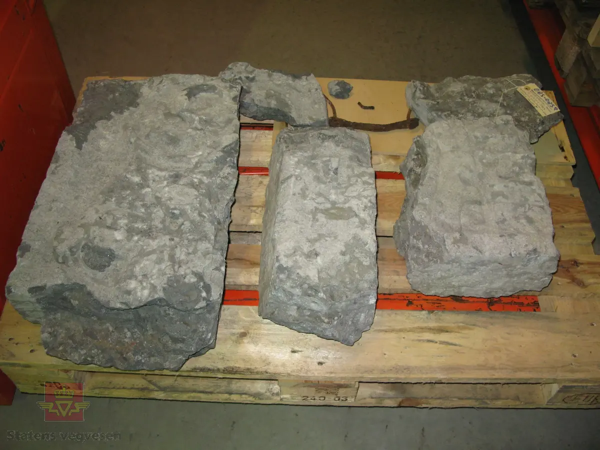 Grå kalkstein i 5 deler. Noe av monogrammet er borte, men 1687 er godt synelig. Kun den største delen er merket. Steinen er lagret på to paller.