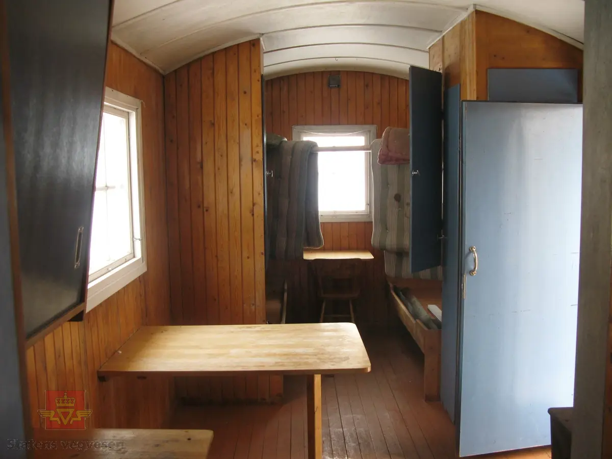 Rød hvilebrakke i tre, med et vindu i hver gavelvegg, ei dør i den ene langveggen og et vindu i den andre langveggen. Dør i gult og vinduskarmer i hvitt og brunt. Stående panel, hjørner har metallbeslag, (i hvitt). Takrenner i stål, (av nyere dato, montert ved NVM). Buet tak kledd med papp. Pipe med hatt. Skjerm over døra. Stigtrinnet ligger inne i brakka. To reflekser på den ene kortveggen. Brakka er innredet med bord, stoler, senger, madrasser, puter, diverse skap og en vedovn av typen Jøtul 380. Blå skap og brunmalt gulv, ellers oljet/lakkert innredning. Hvitt takk innvendig.
