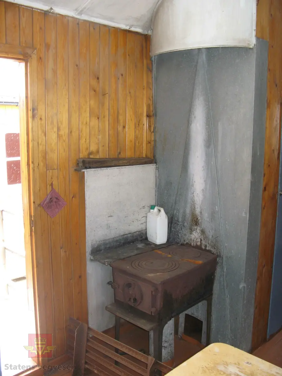 Rød hvilebrakke i tre, med et vindu i hver gavelvegg, ei dør i den ene langveggen og et vindu i den andre langveggen. Dør i gult og vinduskarmer i hvitt og brunt. Stående panel, hjørner har metallbeslag, (i hvitt). Takrenner i stål, (av nyere dato, montert ved NVM). Buet tak kledd med papp. Pipe med hatt. Skjerm over døra. Stigtrinnet ligger inne i brakka. To reflekser på den ene kortveggen. Brakka er innredet med bord, stoler, senger, madrasser, puter, diverse skap og en vedovn av typen Jøtul 380. Blå skap og brunmalt gulv, ellers oljet/lakkert innredning. Hvitt takk innvendig.
