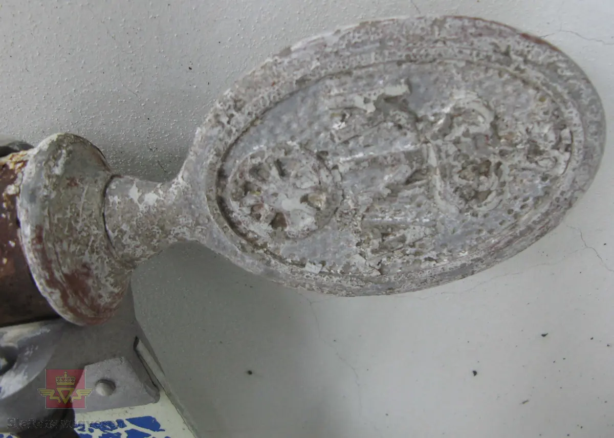 Hvitmalt stolpe, (stålrør), med tre metall-skilt, (aluminium), montert på. På toppen av stolpen sitter et ovalt "KNA-skilt" av, med flens som går innvendig i stolpen. Stolpen har et vegviser skilt av påskrudd, skiltet har symbol for bespisning og overnatting, og teksten "Øyer". Det tredje skiltet på stolpen er uleselig, all tekst mangler. 

