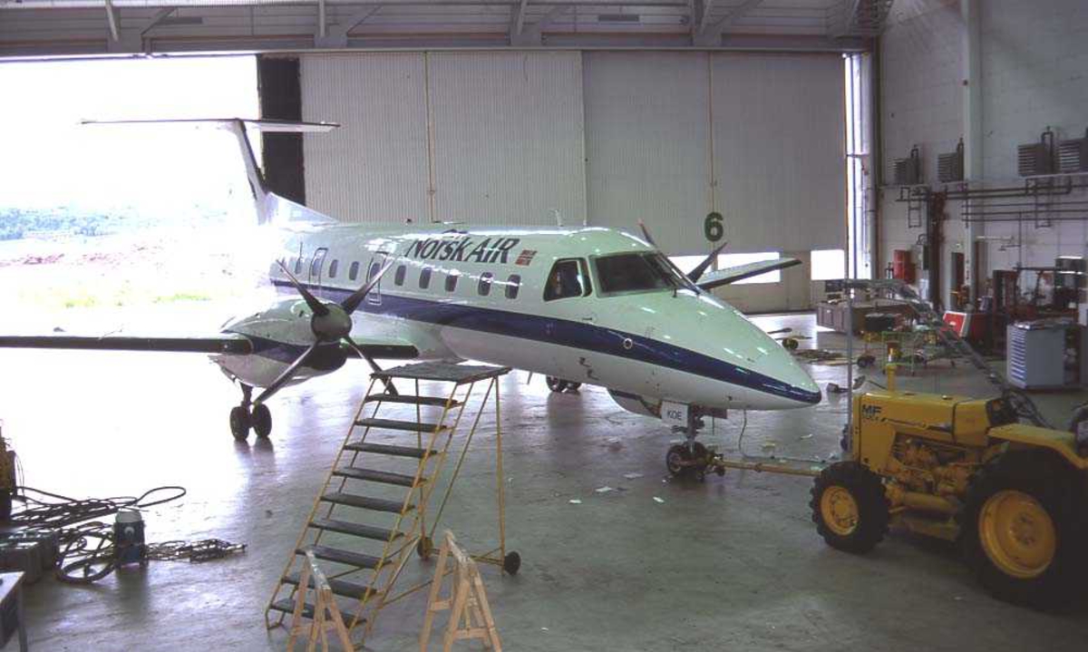 Lufthavn/flyplass. Sandefjord. Widerøes/Norsk Airs hangar. Ett fly, LN-KOE, Embraer EMB-120RT Brasilia.