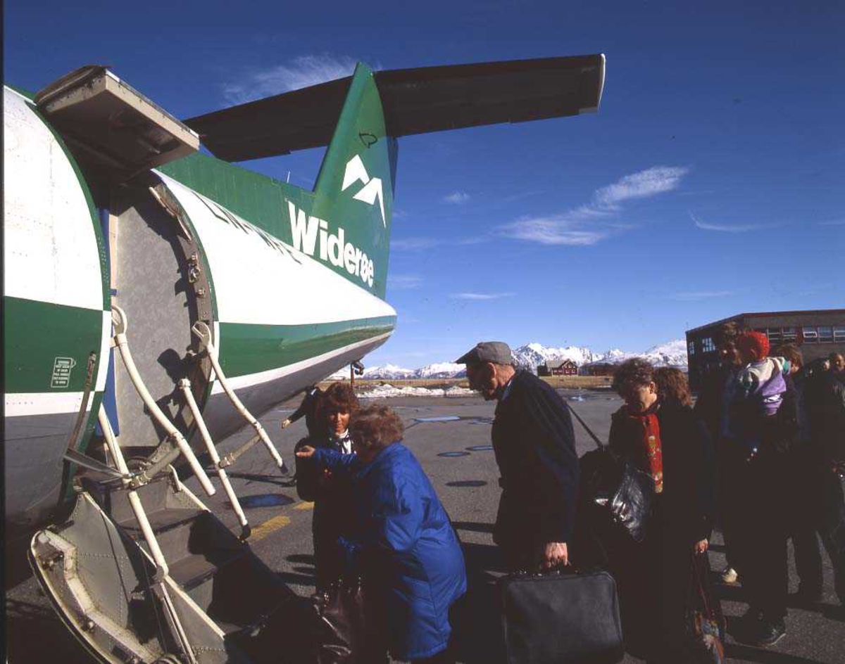 Lufthavn/flyplass. Stokmarknes/Skagen. En kabinpersonale og flere passasjerer foretar ombordstigning. Ett fly, LN-WFE, DHC-7-102/ Dash7, fra Widerøe.