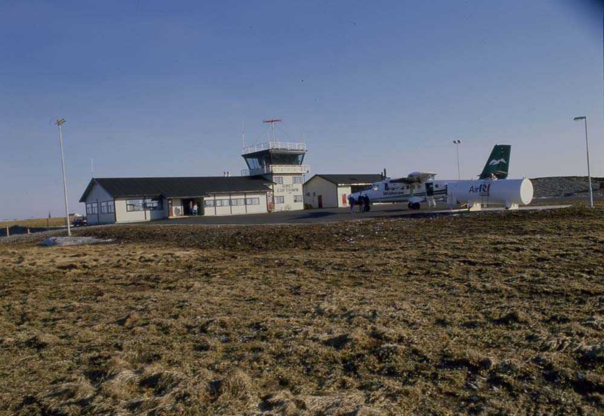 Lufthavn/Flyplass. Røst. Et fly, LN-FKA, DHC-6 Twin Otter fra Widerøe står parkert ved Ekspedisjonen/Flytårnet.