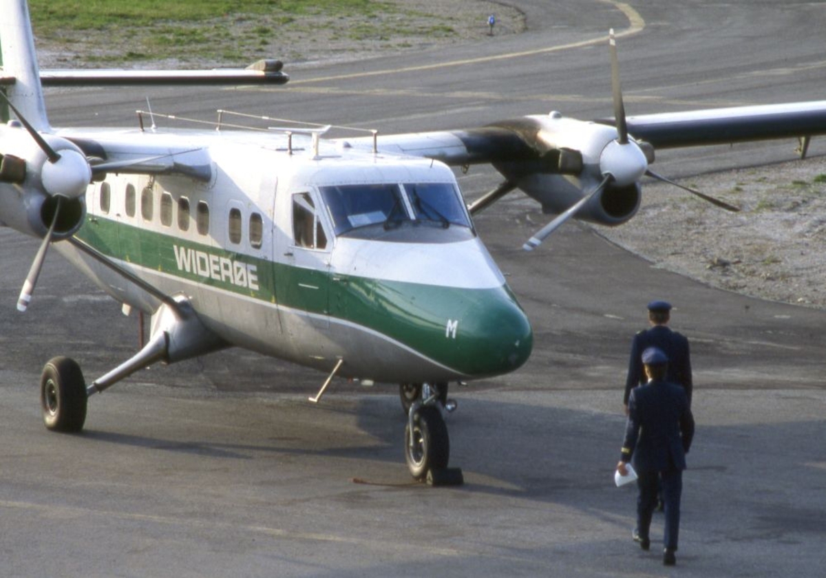 Lufthavn (flyplass). Et fly, LN-BNM DHC-6-300 Twin Otter fra Widerøe parkert. To personer (piloter)