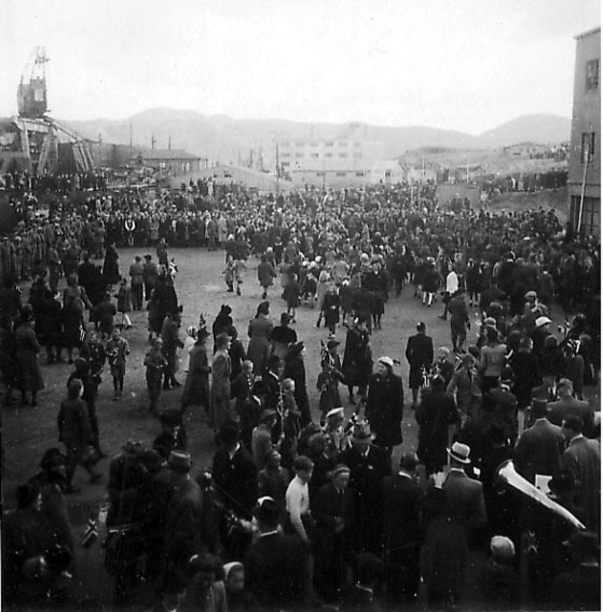 Frigjøringsdagene i Bodø etter krigen 1945. Mange personer i gatene ved kaiområdet, de fleste sivile. Kullkranen til Jakhelln t.v.. Rønvikfjellene bak.