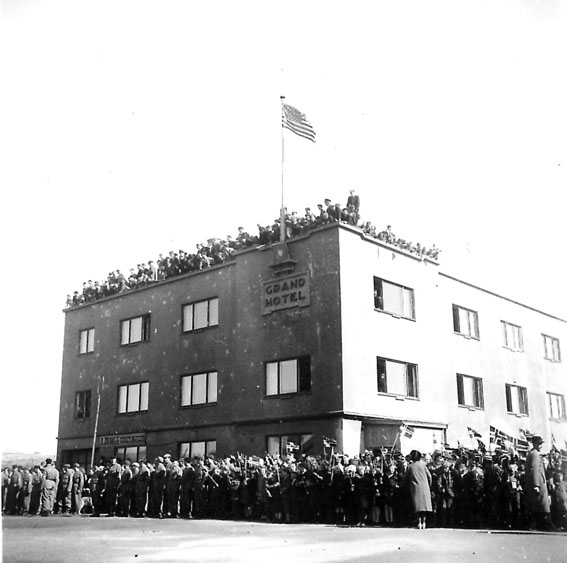 Frigjøringsdagene i Bodø etter krigen 1940 - 1945. Grand Hotel, mange personer på taket og i gata. Amerikansk flagg heist.