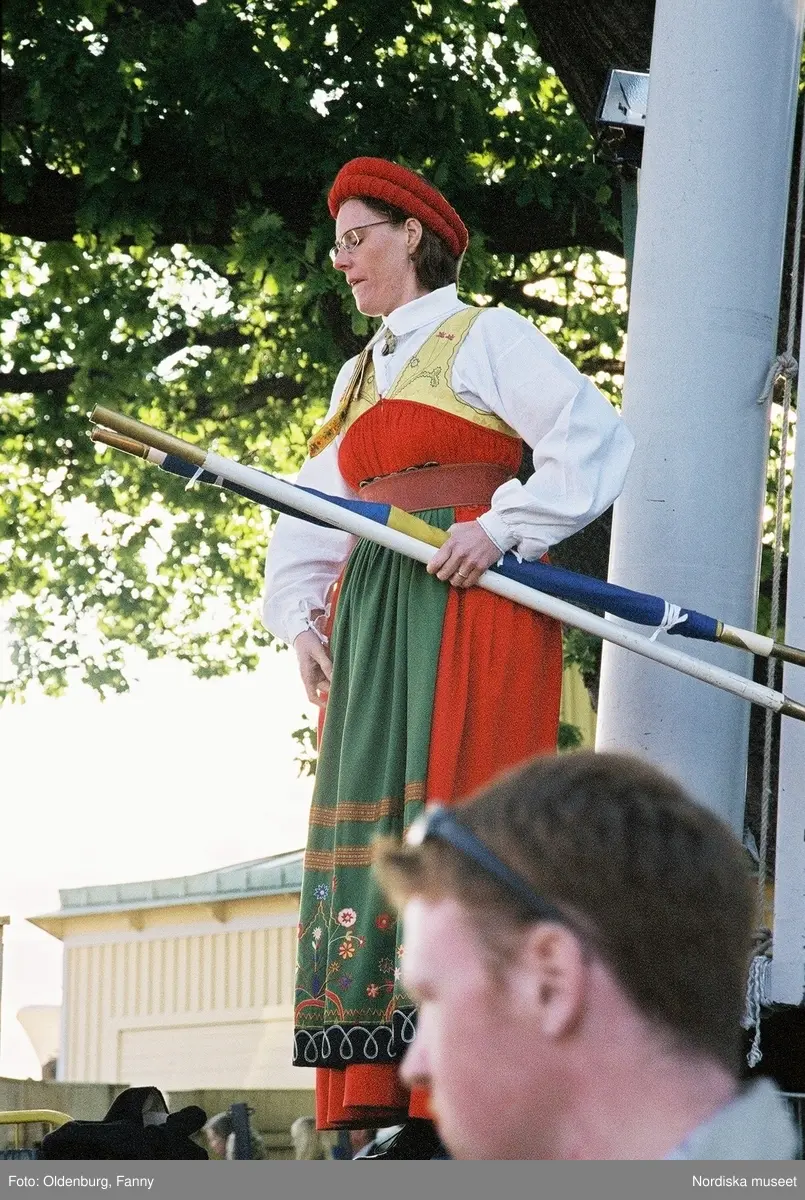 Firandet av den svenska nationaldagen den 6 juni 2004 på Skansen. Människor iklädda folkdräkt. Näsby Parks Scoutkår. Blomsterarrangemang.