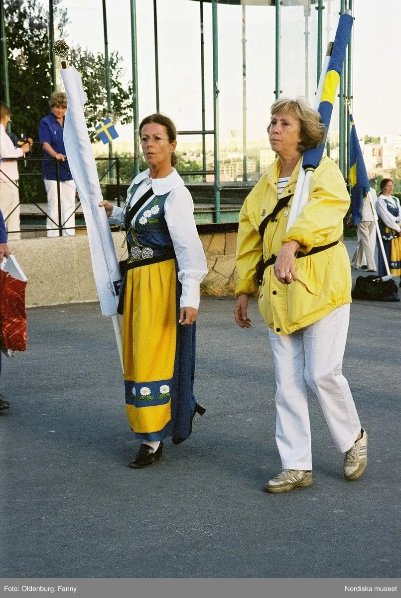 Firandet av den svenska nationaldagen den 6 juni 2004 på Skansen. Människor iklädda folkdräkt. Näsby Parks Scoutkår. Blomsterarrangemang.
