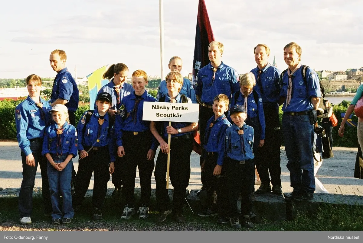 Firandet av den svenska nationaldagen den 6 juni 2004 på Skansen. Människor iklädda folkdräkt. Näsby Parks Scoutkår. Blomsterarrangemang.