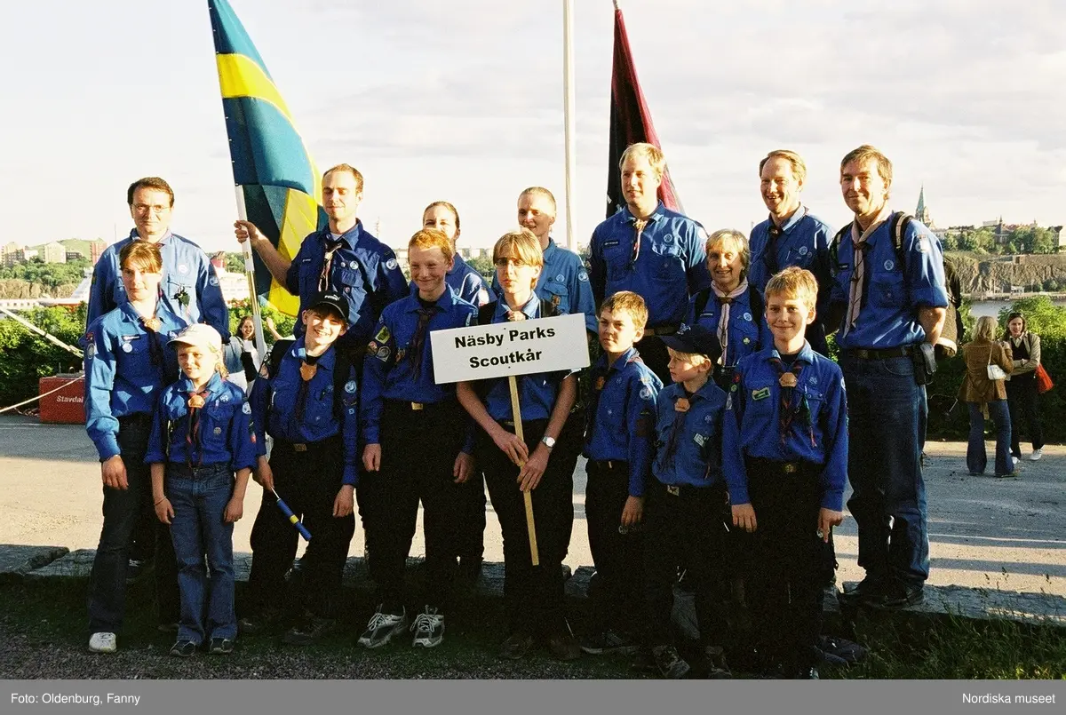 Firandet av den svenska nationaldagen den 6 juni 2004 på Skansen. Människor iklädda folkdräkt. Näsby Parks Scoutkår. Blomsterarrangemang.