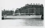 Foto i svartvitt visande passagerarmotorfartyget CHRISTOFER POLHEM vid Nybrokajen, Stockholm, 1955.