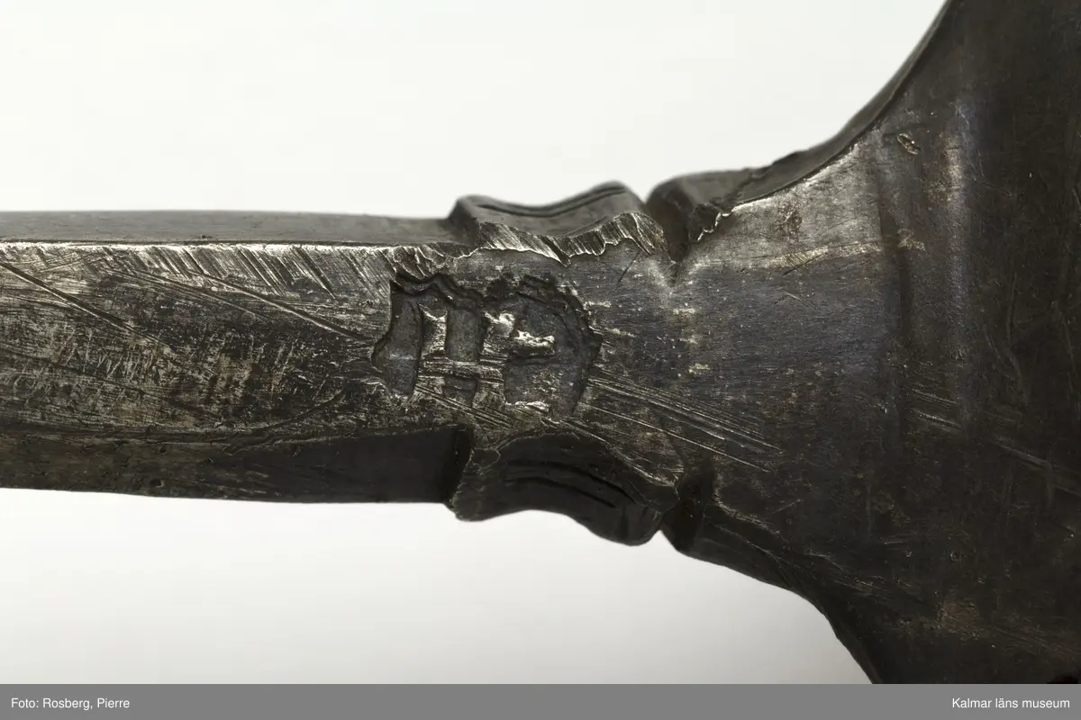 KLM 34757 Sked av metall, silver. Brett ovalt blad med sexkantigt skaft, skaftets avslutning är avbruten. I skedbladet banddekor. Rester av förgyllning, otydlig stämpel. Datering: 1500-tal?