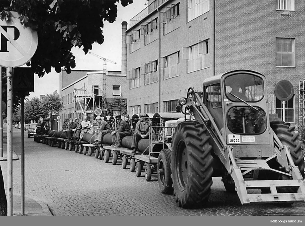 Gummifabriken, leverans av avloppsslang till Strömstad den 28 maj 1959. Traktortåg på Johan Kocksgatan på väg mot hamnen för vidare transport med båt.