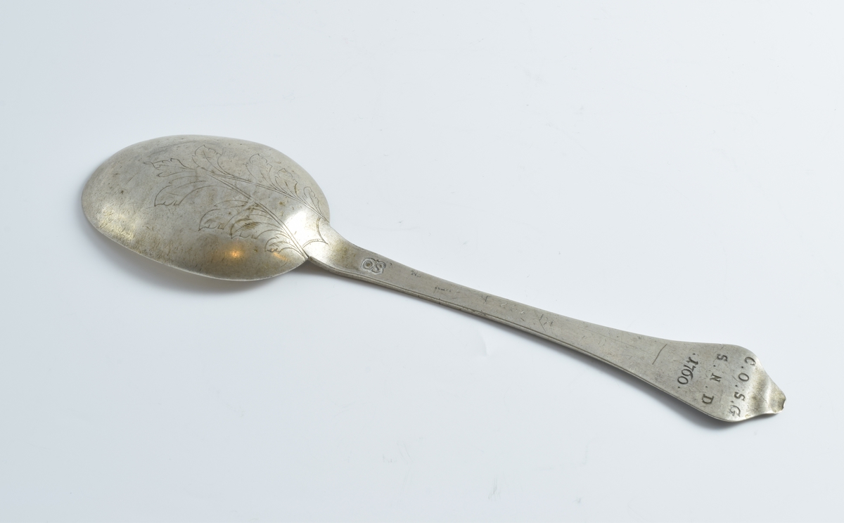 To sølvskjeer med gravert bladornament på baksiden av bladet.