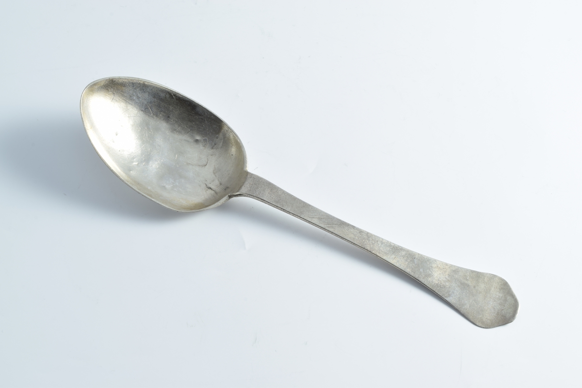 To sølvskjeer med gravert bladornament på baksiden av bladet.