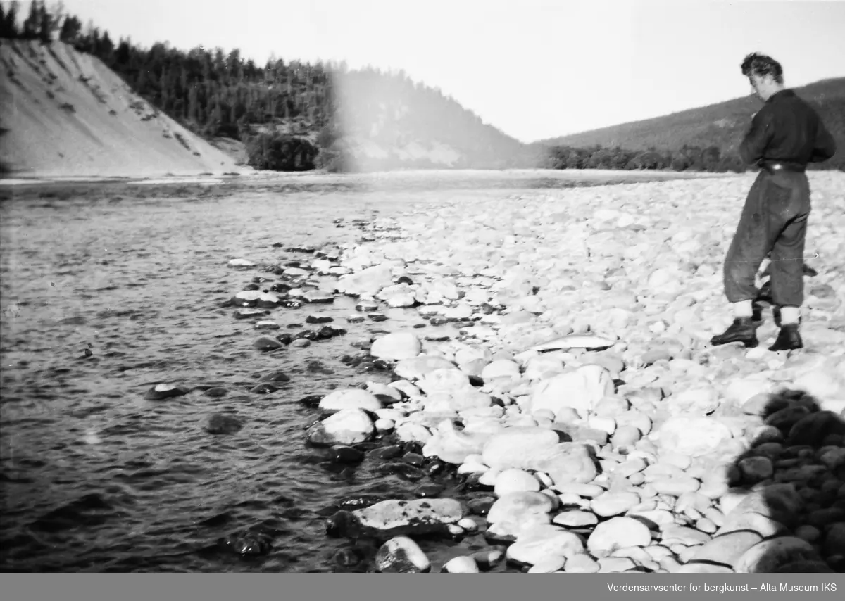 Roar står ved elvebredden.
Bildet er tatt i fiskesesongen på sommeren i 1949.