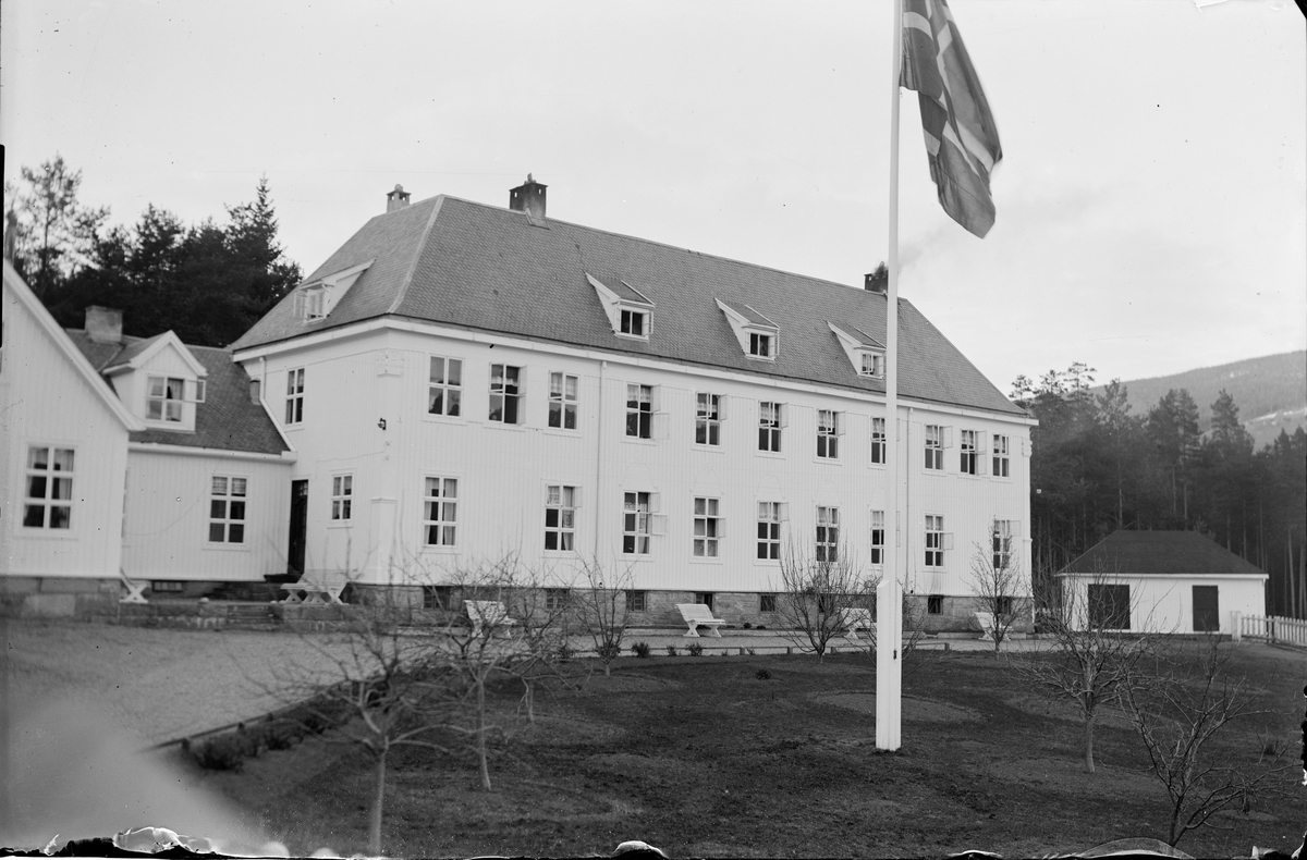 Tinn Helseheim med park og krakker på utsiden. Åpne vinduer i bygget. Flaggstang med norsk flagg.