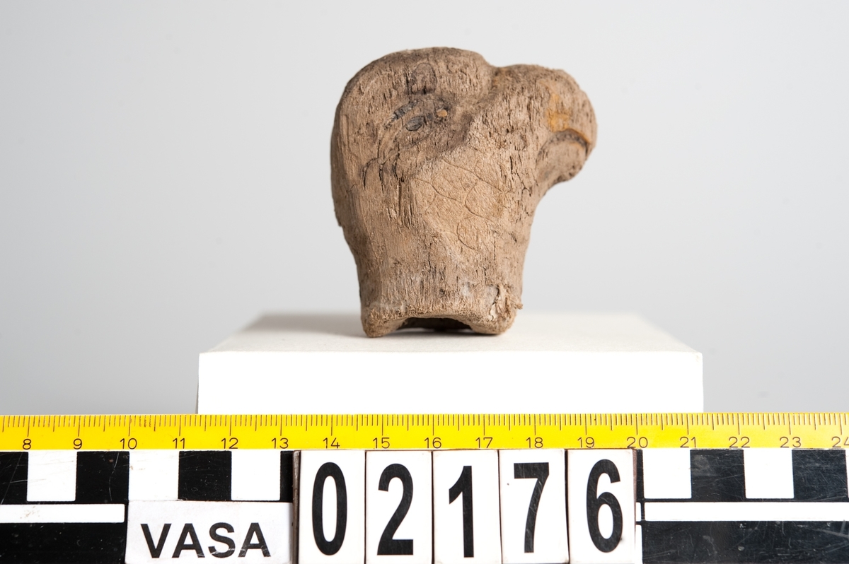 Litet, skulpterat fågelhuvud, troligtvis papegoja. Fågeln har en böjd näbb samt ett smalt öga. På undersidan av huvudet finns ett runt hål/urtag.
Skulpturen är mycket ömtålig, med småsprickor. Den ena sidan av fågelhuvudet är mycket nött och något tillplattat.