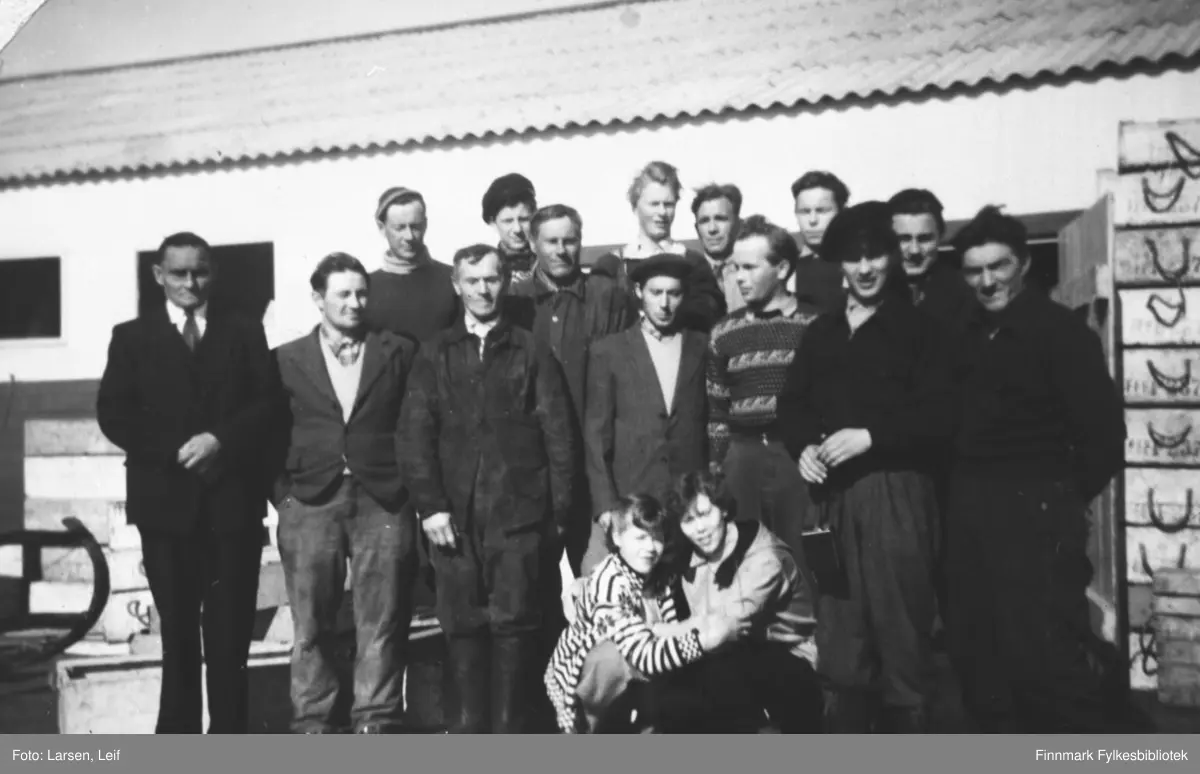 Arbeidsgjeng hos Warholm på kaia i Tyfjord i 1956. De to barna som sitter er Karl Gustav Sivertsen og hans eldre søster Ragnfrid (Gulle) Sivertsen. Helt til høyre står Trygve Larsen. Hans sønn Leif Larsen har tatt dette bildet. De andre er ukjente navn. Trygve Larsen med kona bodde i Hamna under Hamnesset, huset står der ennå.

Vår informant (Ragnar Mortensen) forteller at det var mange fra Tana som kom til Tyfjord for å fiske, søke fiskearbeid og jobbe med line-egning. Det kan se ut som det er søndag, alle er "søndagskledde" som det het på denne tiden. Etter storbrannen på slutten av 1970-årene har Tyfjord vært ubebodd.

 "Tyfjorden (nordsamisk: Dáigevuotna) er en fjordarm av Tanafjorden på østsiden av Nordkinnhalvøya i Gamvik kommune i Finnmark. Fjorden har innløp mellom Hanstyske i nord og Tyfjordneset i sør og strekker seg 4,5 kilometer vestover til Tyfjord i bunnen av fjorden." iflg. Wikipedia. Tyfjord er en gammel bygd ved fjorden. Det er ingen annen bebyggelse her.
