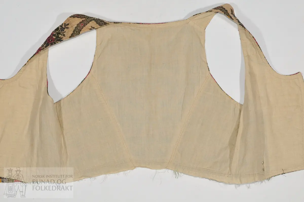 Liv i brosjert stoff av viskose. Maskinsydd. Vunne på basar i 1950

Mål
- rygglengde 31cm
- ryggbreidde 25cm
- høgde under arm 18cm