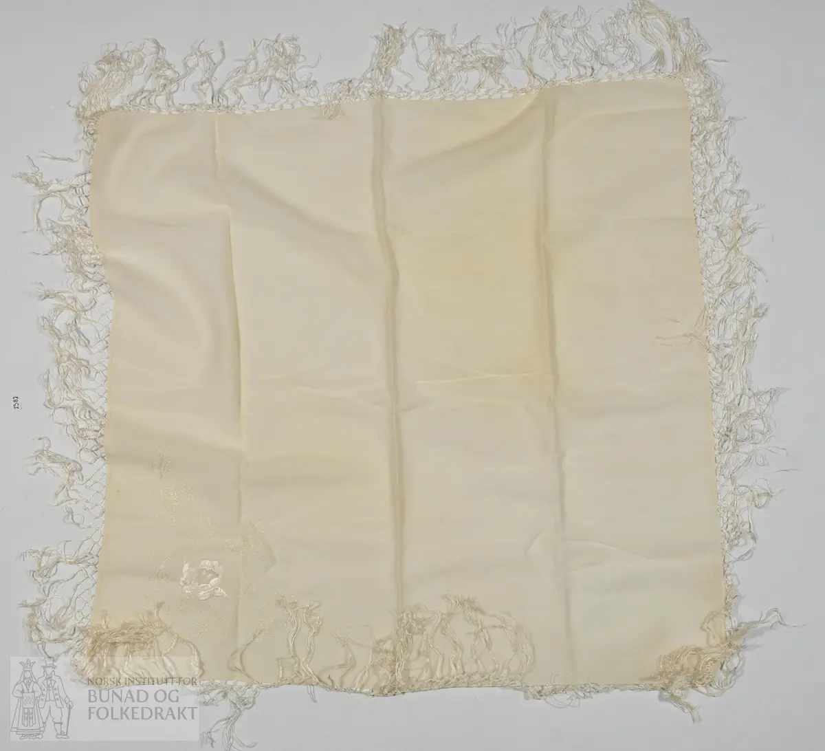 Kvitt ullsjal med tamburering og frynser. 
Mål: 67cm x 70cm