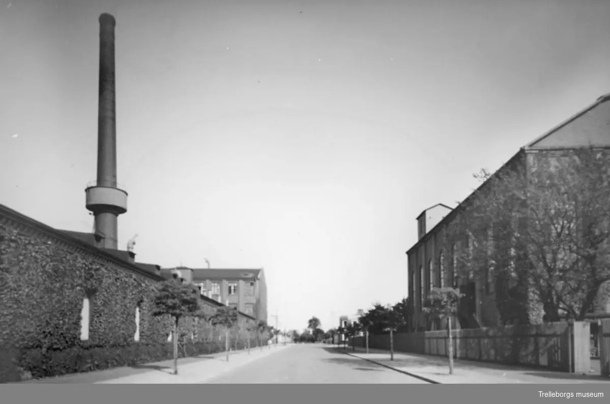 Nygatan (idag 2016 Henry Dunkers gata) österut från korsningen med Johan Kocksgatan. Till vänster byggnad 2, uppförd 1897, med den gamla fabriksskorstenen med släckvattenbehållare. Där bakom Tekniskan, byggnad 10, uppförd i en våning 1909 och påbyggd med ytterligare två våningar 1913. Till höger Ångcentralen, byggnad 34, uppförd 1927-1928.